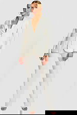 Model wearing an off-white tailored pantsuit with shawl lapel and button closure, front view.