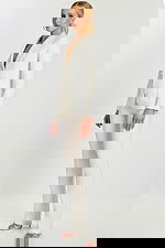 Side view of model in elegant off-white pantsuit with structured fit and satin lapel.