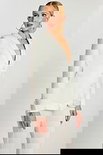 Model in off-white pantsuit featuring a smooth silhouette, satin accents, and long sleeves.