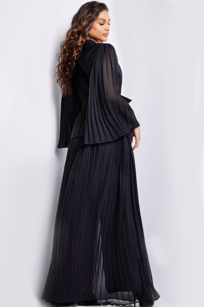 Model showcasing the back of Jovani 26024 black gown with pleated skirt.