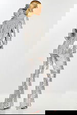 Back view of model in shimmering silver sequin pantsuit featuring tailored jacket and wide-leg trousers.