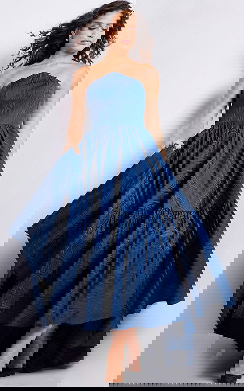 Model wearing Jovani 26152 navy strapless dress with full skirt.