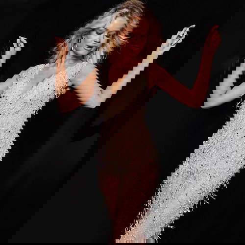 Model wearing Jovani 32592 nude gown posing with arms up, showcasing front details.