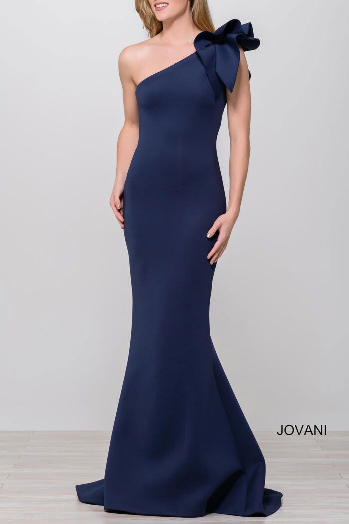 Model in Jovani 32602 navy gown, one-shoulder with bow