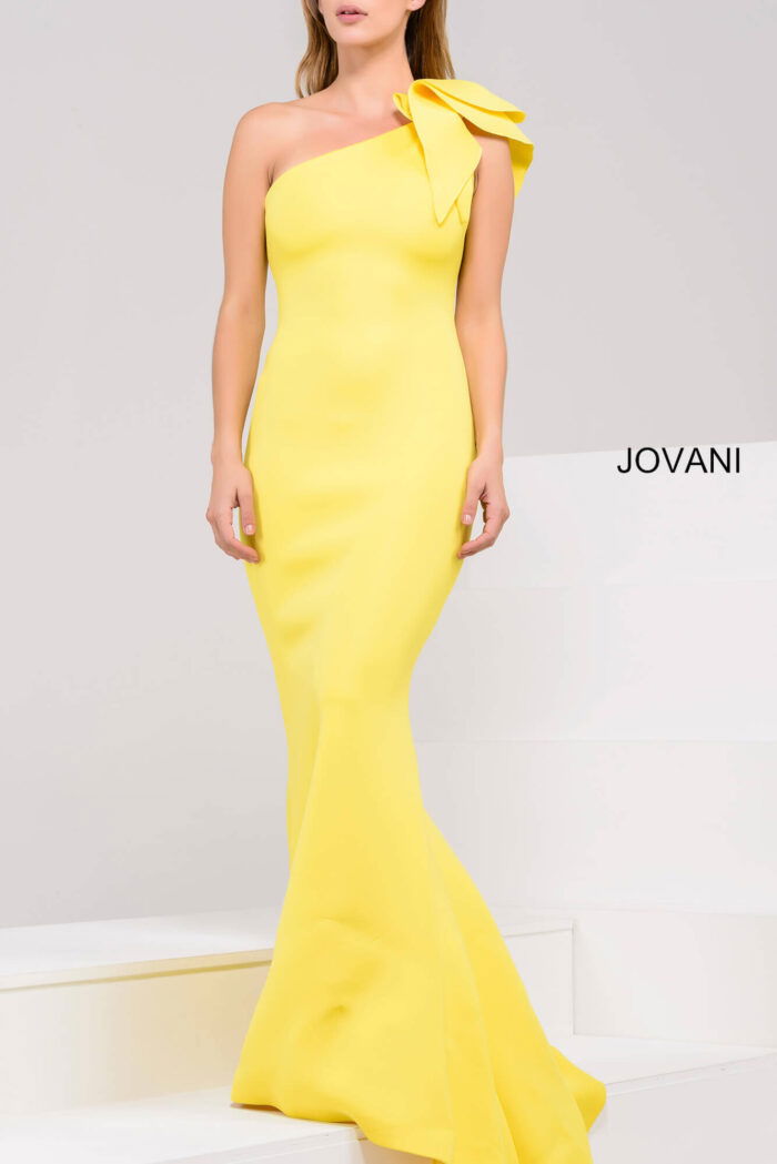 Model in Jovani 32602 yellow gown with one-shoulder bow detail