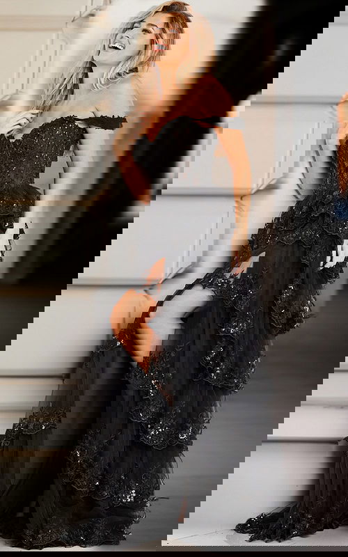 Model wearing Jovani 36687 black gown with tiered lace and sequin details.