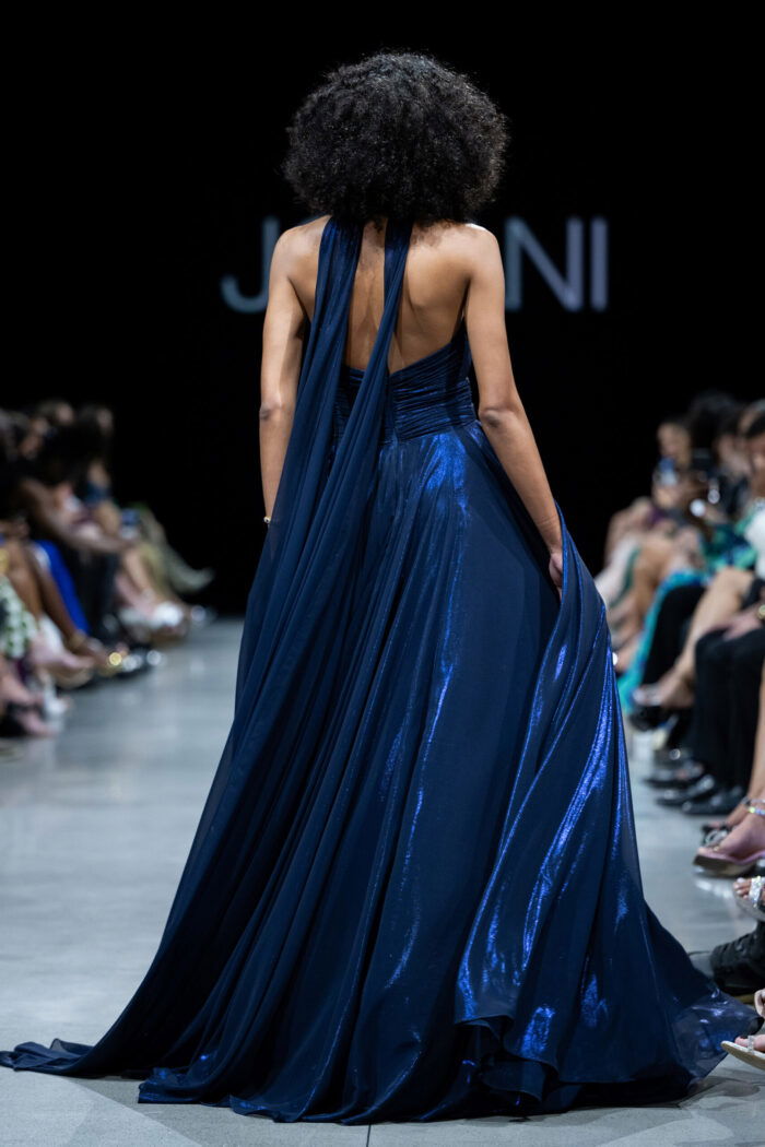 Model showing back of Jovani 37163 navy gown with dramatic train.