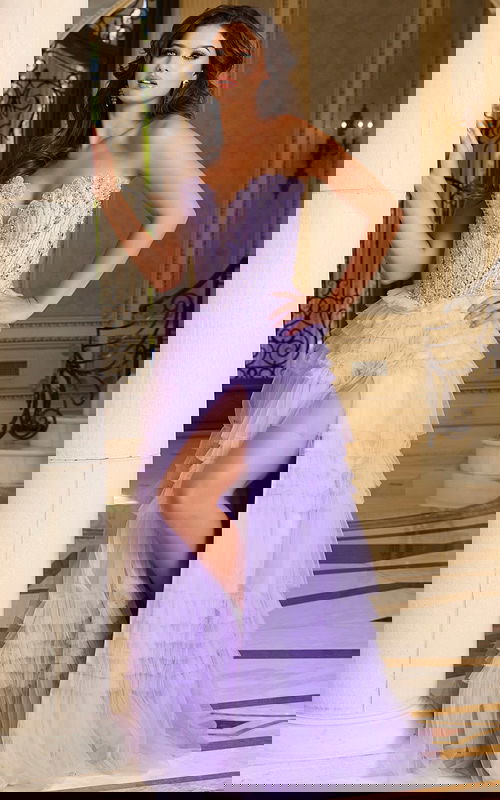 Model wearing Jovani 37197 lilac gown with beaded bodice and ruffled skirt, showcasing a high slit.