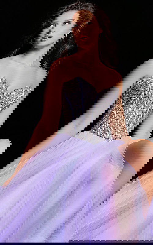 Model wearing Jovani 37199 lilac gown showing tulle detail and embellished bodice, seated pose.