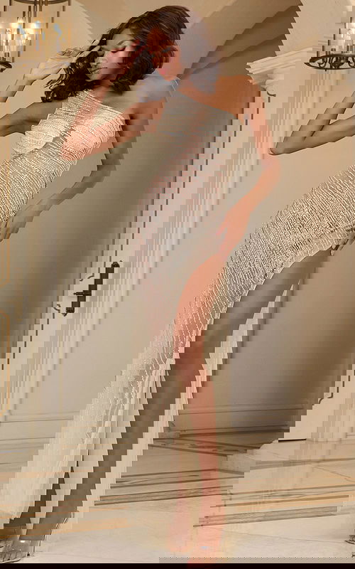 Model wearing Jovani 37211 nude floor-length gown with one-shoulder neckline and shimmering details, featuring a high slit.