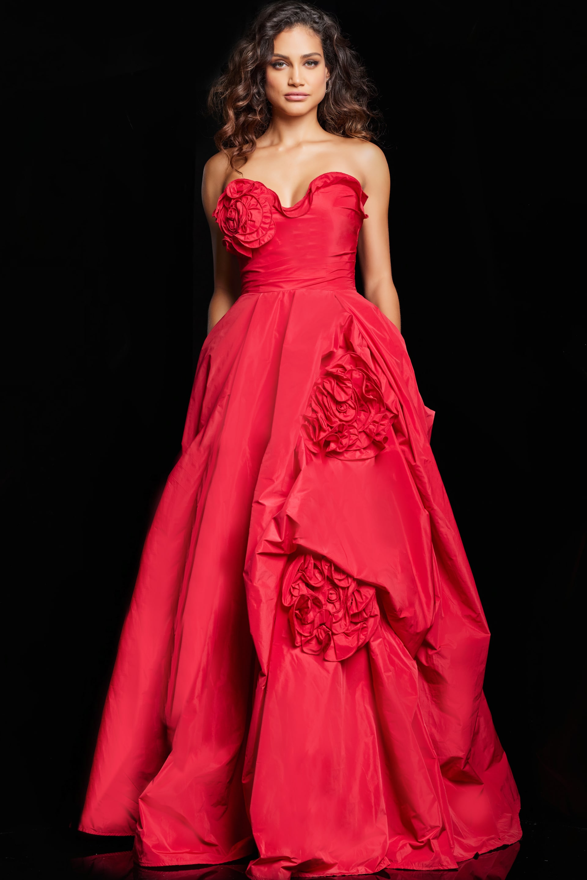 37266_RED_9.jpg Model wearing Jovani 37266 red gown with rosette embellishments from front view.