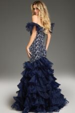 Model wearing Jovani 38115 navy mermaid dress with ruffled train, back view.