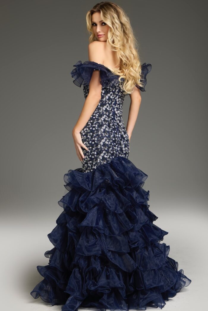 Model wearing Jovani 38115 navy mermaid dress with ruffled train, back view.