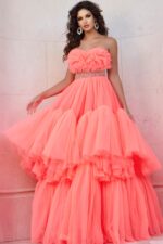 Model wearing Jovani 38299 orange gown with floral ruffles and embellished waist, front view.