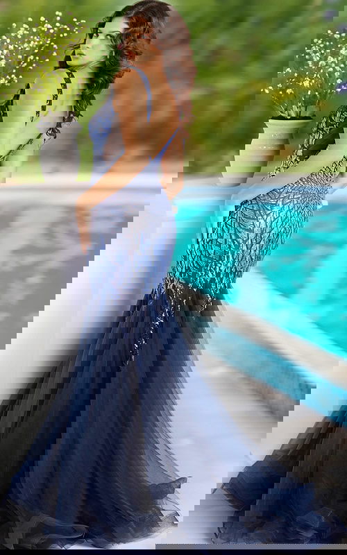 Model wearing Jovani 38373 navy mermaid gown with sequin bodice and tulle skirt, back view.