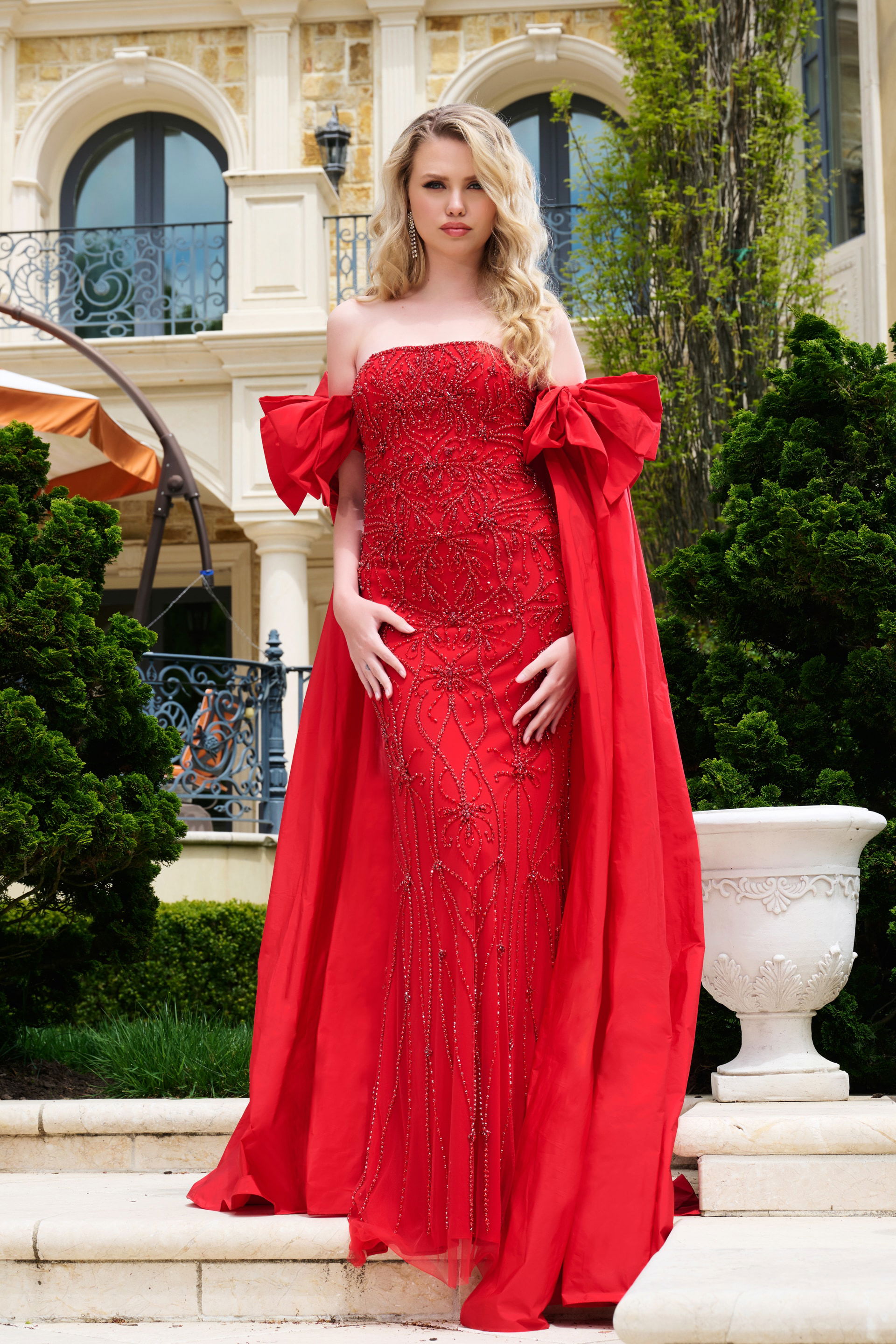 39377-RED-202.jpg Model wearing Jovani 39377, red gown with intricate beadwork and dramatic bows, front view.