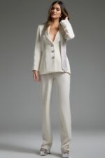 Model wearing Jovani 39726 ivory pant suit with silver embellishments, front view.
