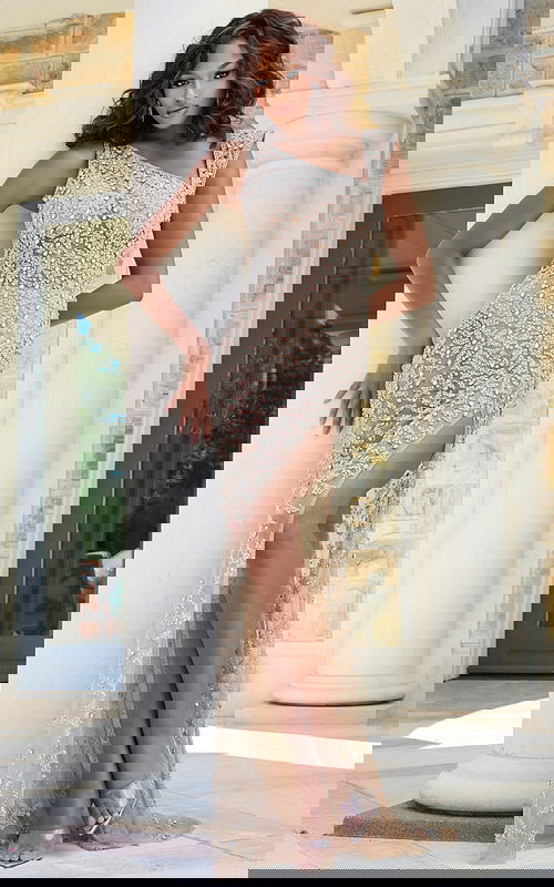 Model wearing Jovani 39849 nude gown with beaded design and high slit, front view.