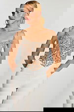 Model wearing silver beaded corset-style top with white fitted pants, front view.