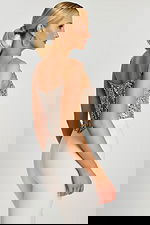 Side angle of model in silver sequin corset top paired with high-waisted white pants.