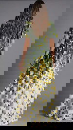 Rear view of a floor length gown with green and yellow floral print and flowing skirt