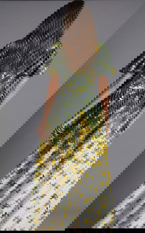 Rear view of a floor length gown with green and yellow floral print and flowing skirt