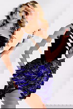 Woman wearing a black velvet one-shoulder dress with purple satin rosettes