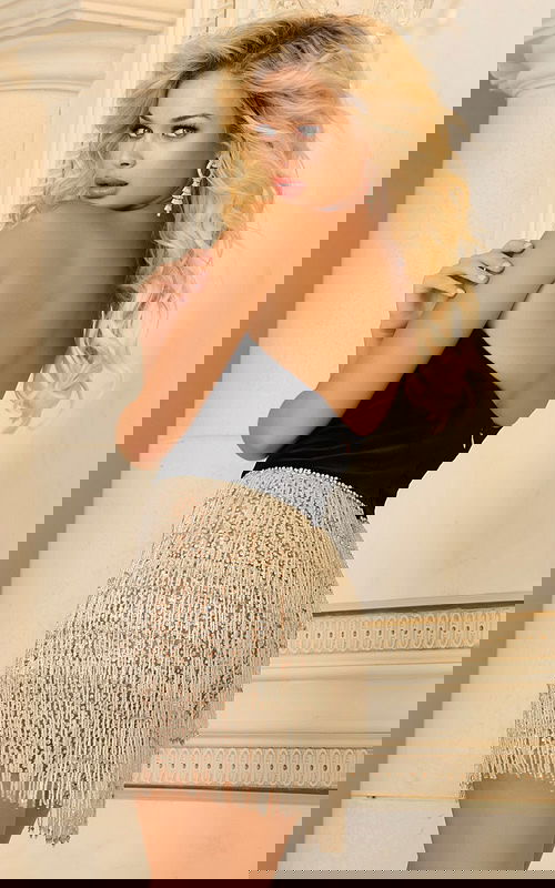 Model wearing Jovani 40143 black dress with sweetheart neckline and fringe skirt, back view.