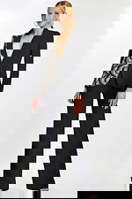 Model wearing black pantsuit with asymmetric sequin detailing and plunging neckline.