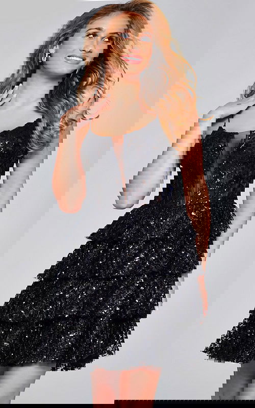 Model wearing Jovani 40386 black mini dress with sequined tiered skirt and illusion neckline.