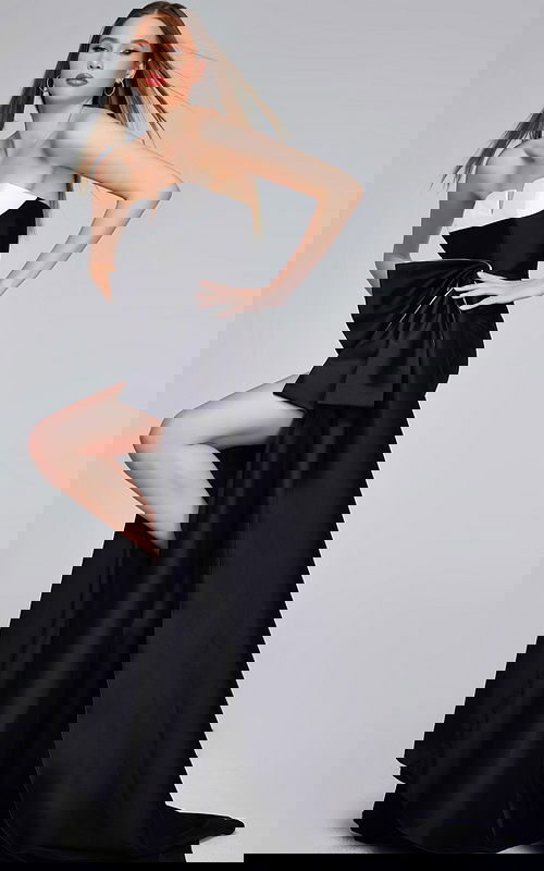 Model wearing Jovani 40792 black gown with high slit and bow detail.