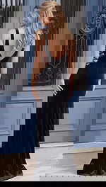 Back view of a sleeveless evening gown with an open back, lace up sides, and flowing skirt