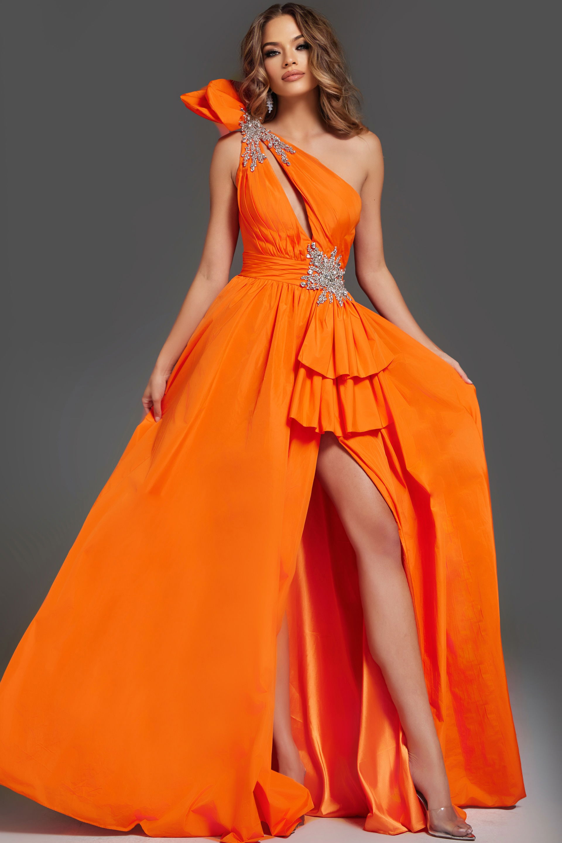 40929-2 Model wearing Jovani 40929 orange one-shoulder gown with ruffle detailing and high slit