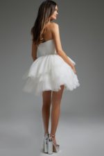 Model wearing Jovani 41054 white dress showing layered skirt, back view.