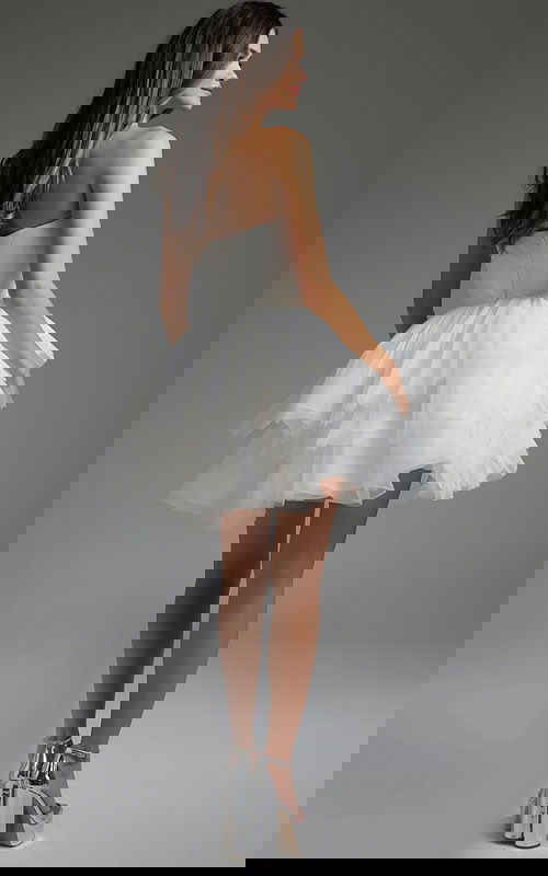 Model wearing Jovani 41054 white dress showing layered skirt, back view.