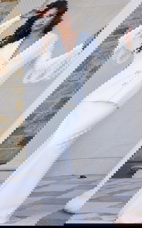 Model wearing Jovani 42121 ivory gown with deep V-neckline and fringed sleeves.