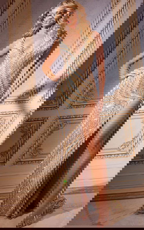 Model wearing Jovani 42512 nude beaded gown with V-neckline and high slit, front view.