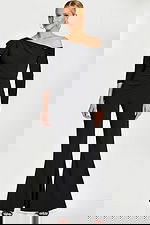 Model in fitted black jumpsuit with dramatic shoulder pleats and flare legs