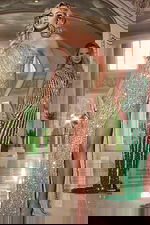 Model wearing Jovani 42677 gold gown with sequined design and high slit from the front