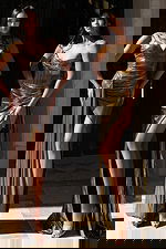 Two models wearing shimmering metallic fitted gowns with corset and V-neck styles