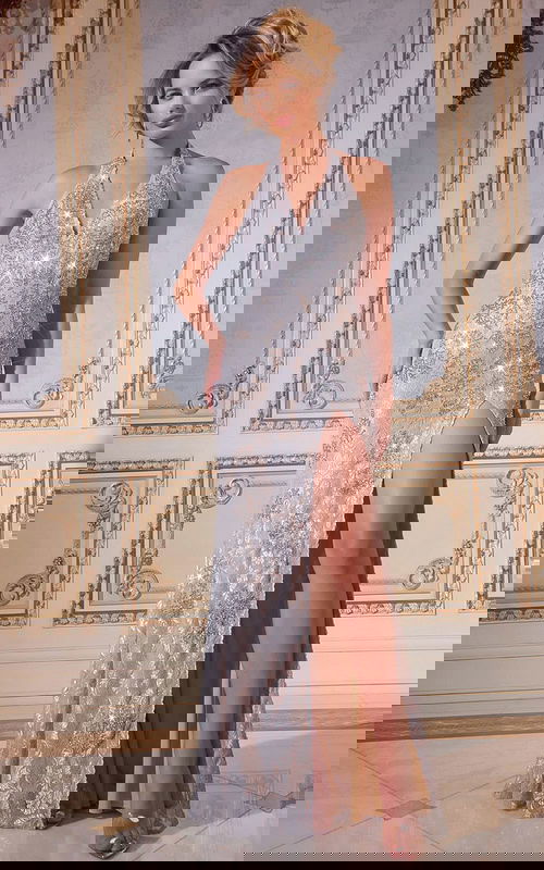 Model wearing Jovani 43098 silver gown with halter neckline and high slit, front view.