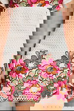 Close-up of skirt with bold pink and orange floral embroidery on white eyelet fabric