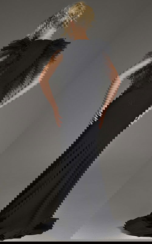 Model wearing Jovani 43153 black dress with flutter sleeves, back view.