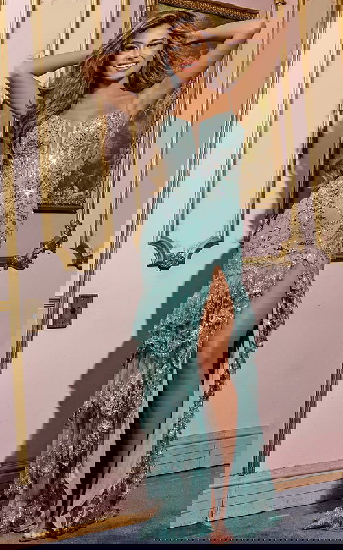 Model wearing Jovani 43171 green evening gown with high slit and embellishments, front view.