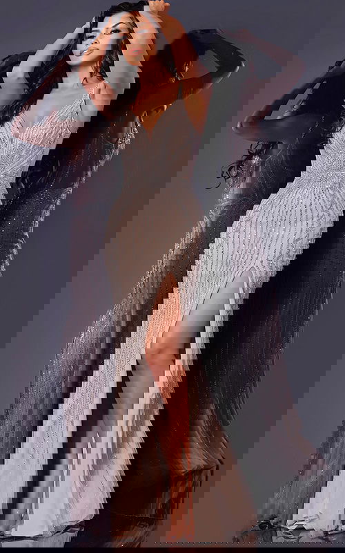 Model wearing Jovani 43221 stunning silver gown with beaded details and high slit.