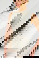 Close-Up Of Ivory Sleeveless Top With Fabric Buttons And Notched Flap Pockets