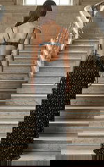 Back view of a fitted gown with an open back, thin straps, and intricate beaded detailing