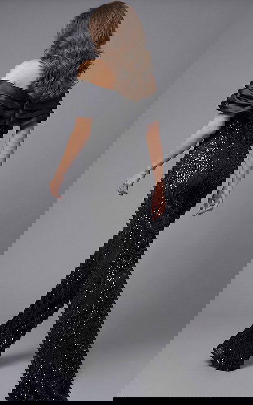 Back view of beaded wide leg jumpsuit with off shoulder draped neckline, fitted waist, and flowing pants