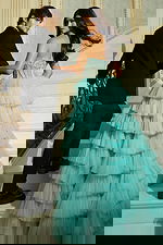 Model posing on staircase in ruffled tulle gown with elegant train