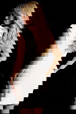 Sleeveless fitted white dress with black neckline detail and draped waist